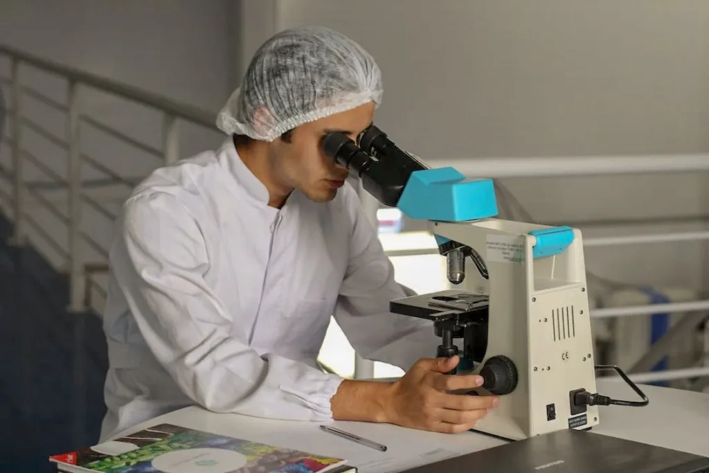 man with head covered, observing under a microscope