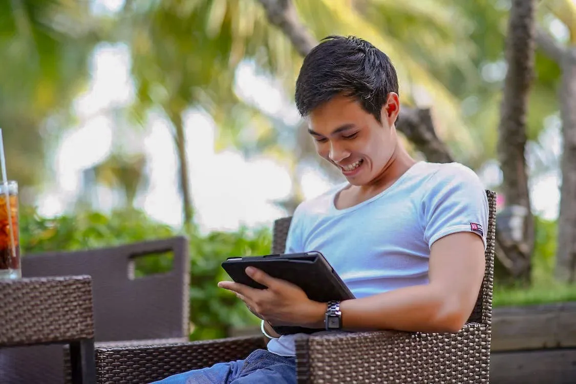man in white t shirt smiling at the tablet in outdoor - First Impressions in Online dating
