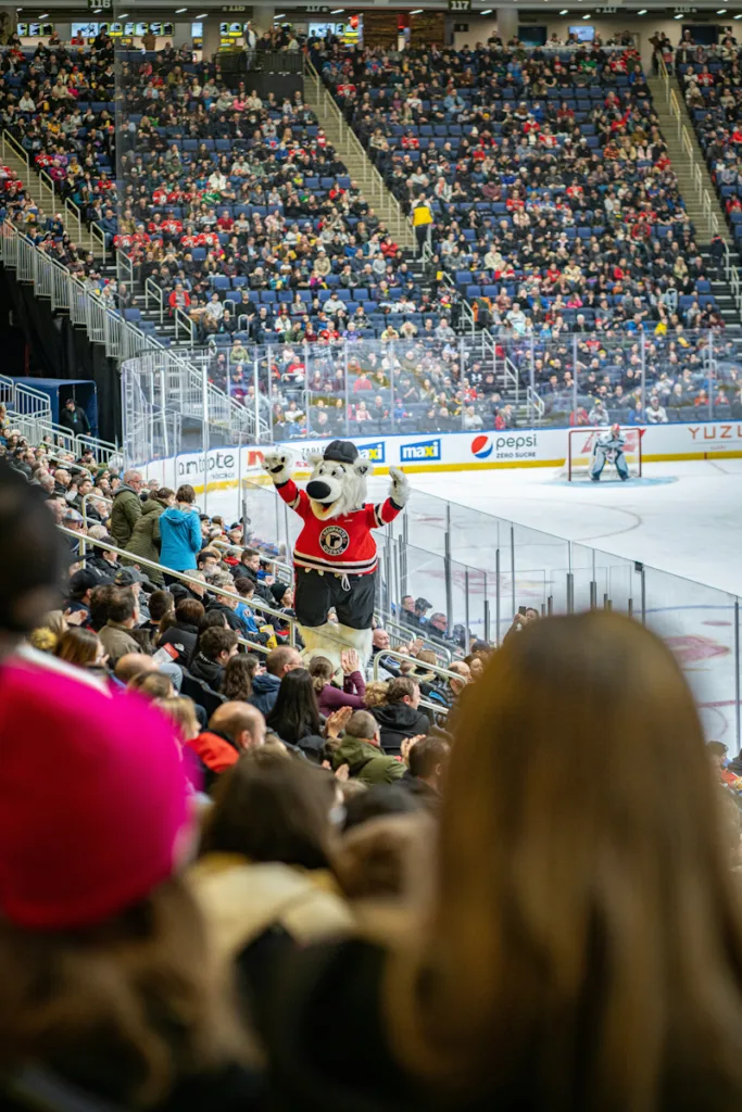 Mascot in a ice hockey stadium cheering the crowd.