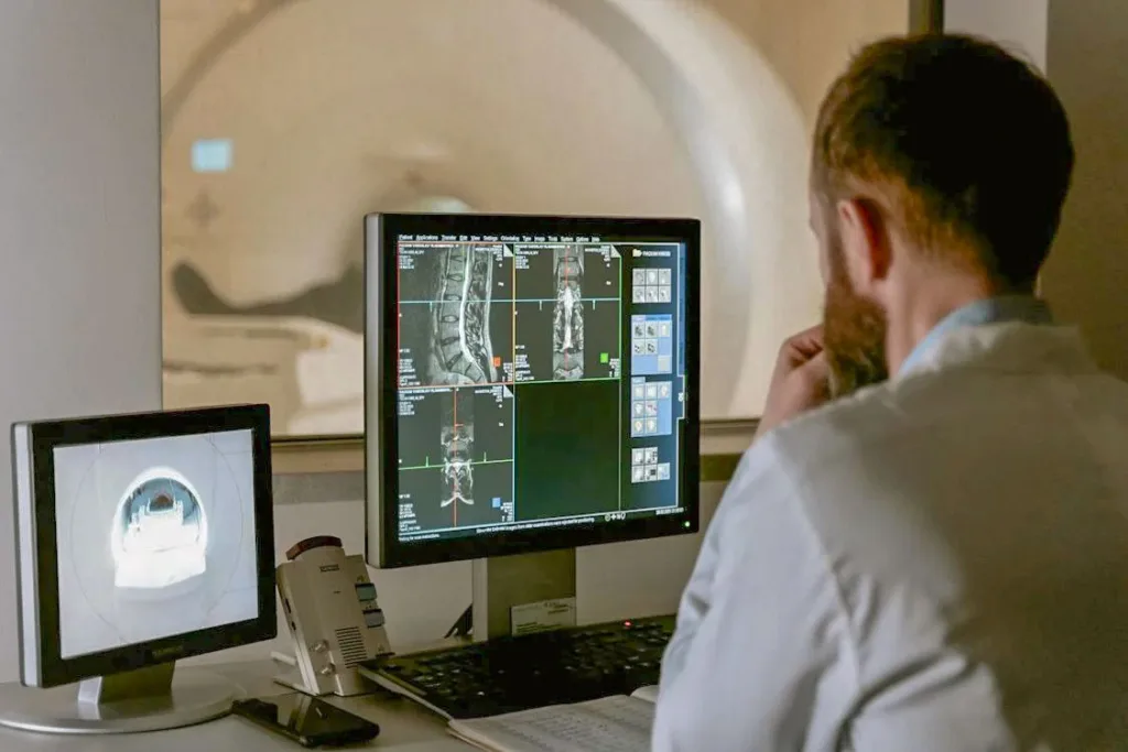 man in white overcoat looking at screen with x-ray scans observing