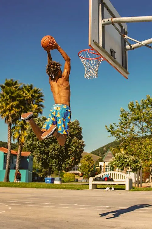 shirtless youth in blue shorts playing basketball