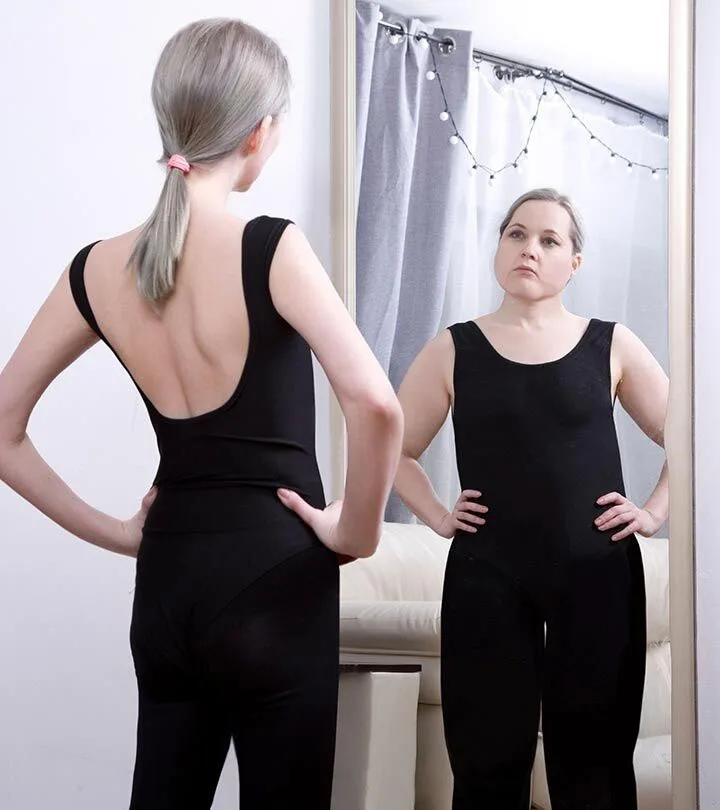 slim woman in black yoga jumpsuit standing in front of mirror and reflection is of fat woman