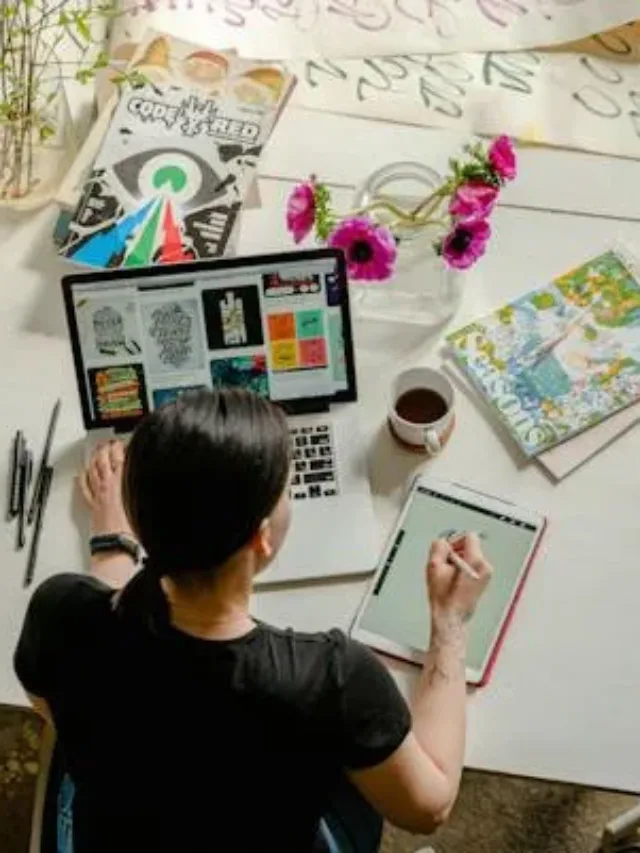 Working professional on a white desk using left hand on laptop and write hand on a drawing pad