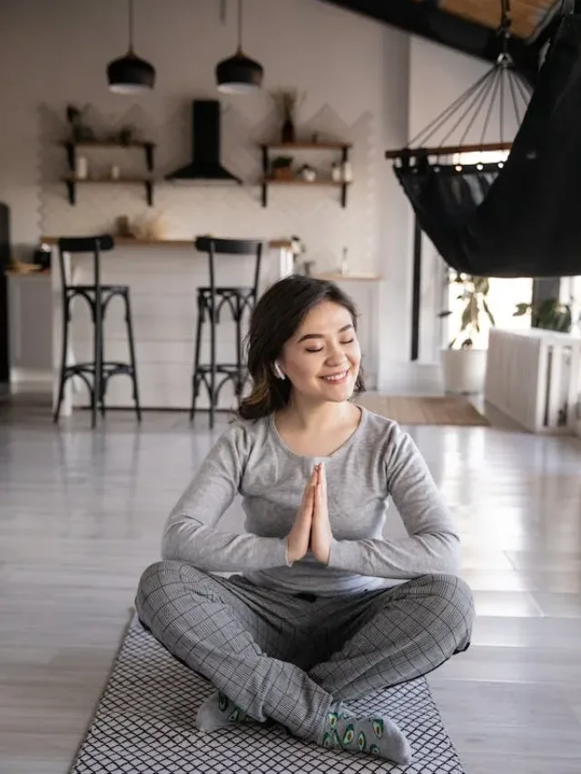 smiling woman in folded legs and hands with closed eyes