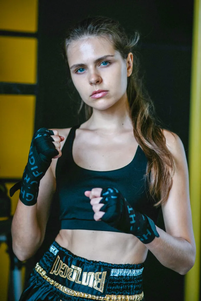 woman giving intense look with boxing fist pose in short tank top and black boxing shorts