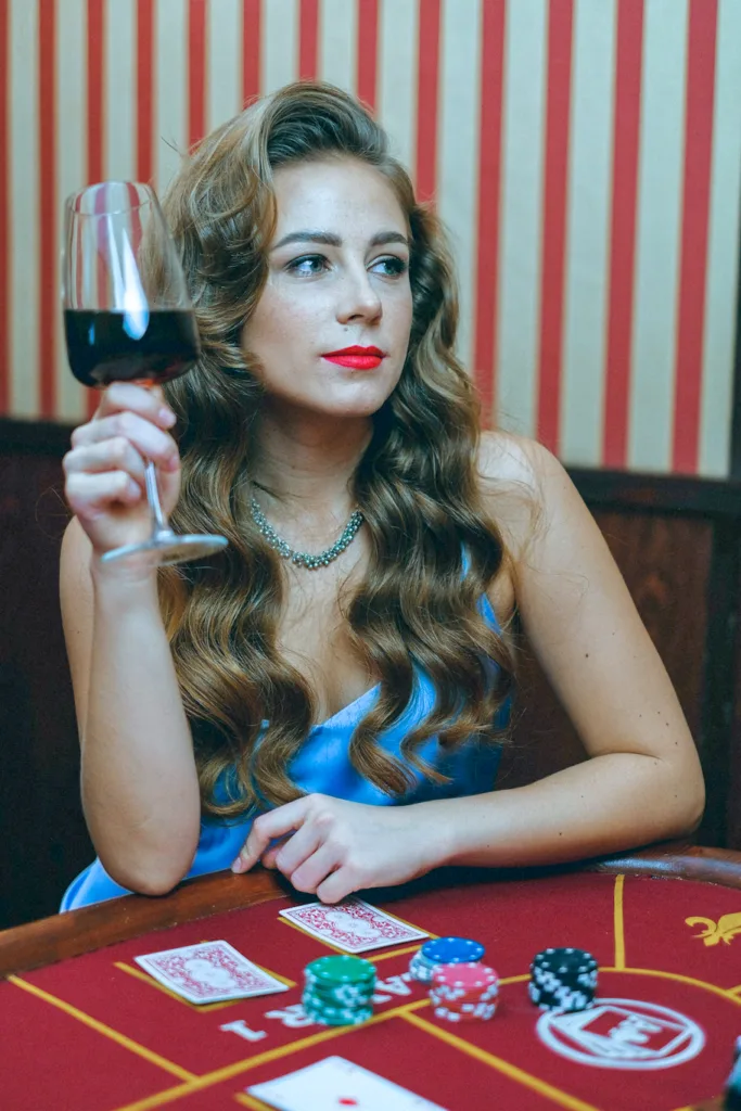 woman in blue dress holding a glass of wine on a casino table