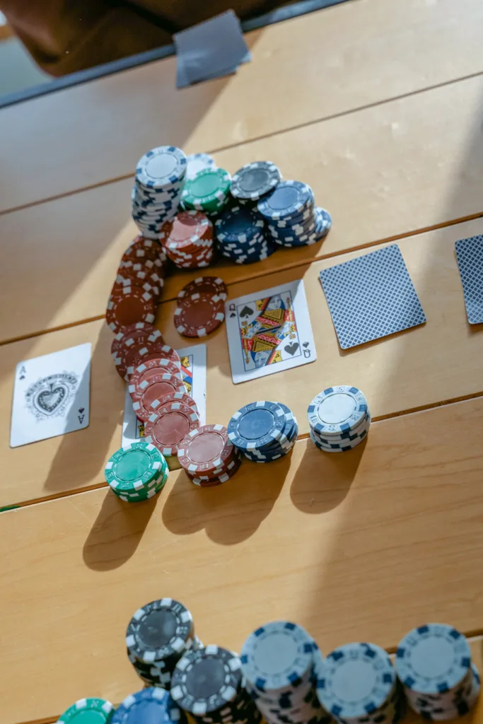 stack of chips and playing cards on a brown table
