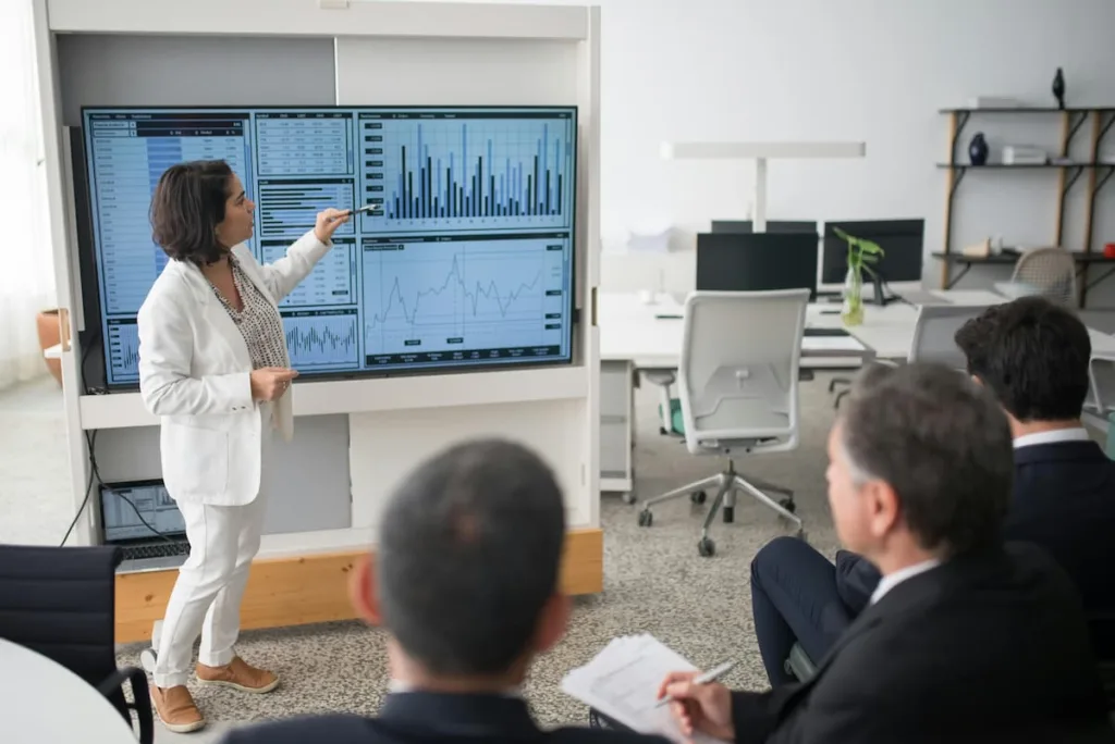 woman in white coat and white pants explaining Advanced US Stock Market Predictive Method to an audience