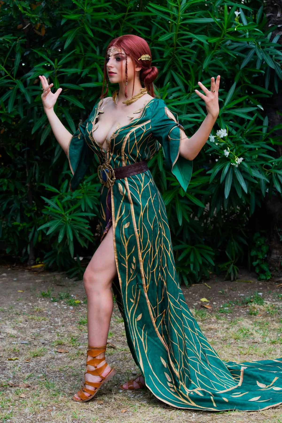 woman in green long gown with thigh slit in cosplay suit with hands gesture
