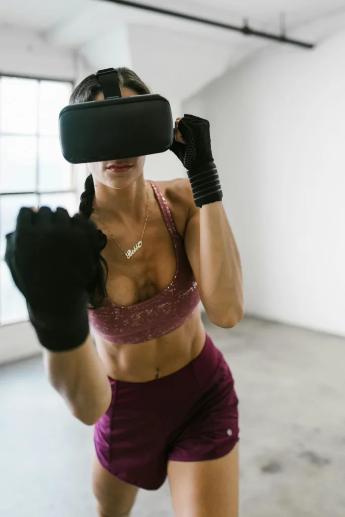 Woman with VR headset in shimmering pink sports bra and boxing pants in posture