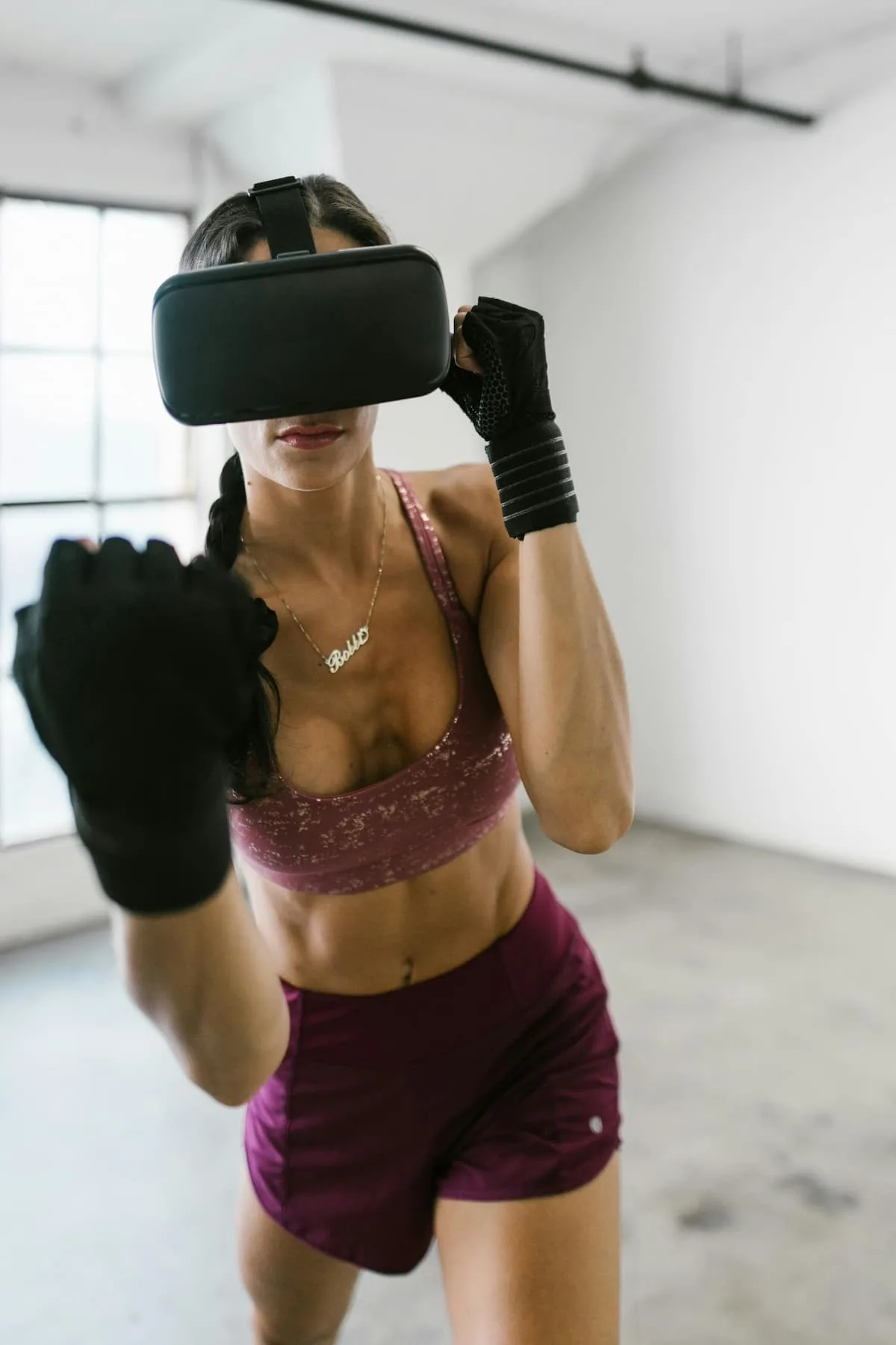 Woman with VR headset in shimmering pink sports bra and boxing pants in posture