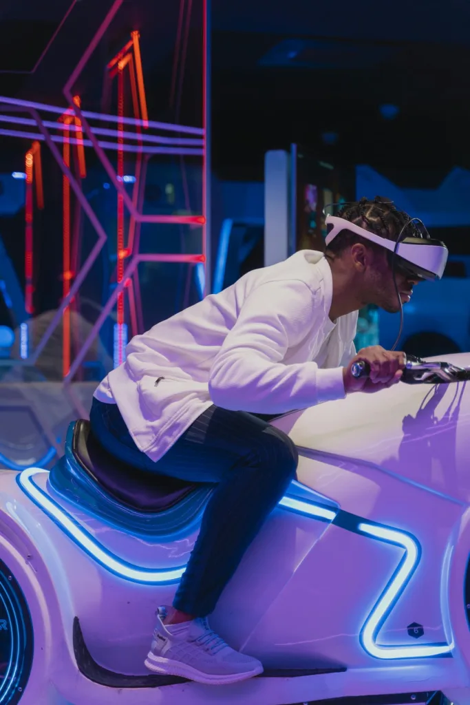 Man with white jacket on a white bike with VR headset inside a game zone