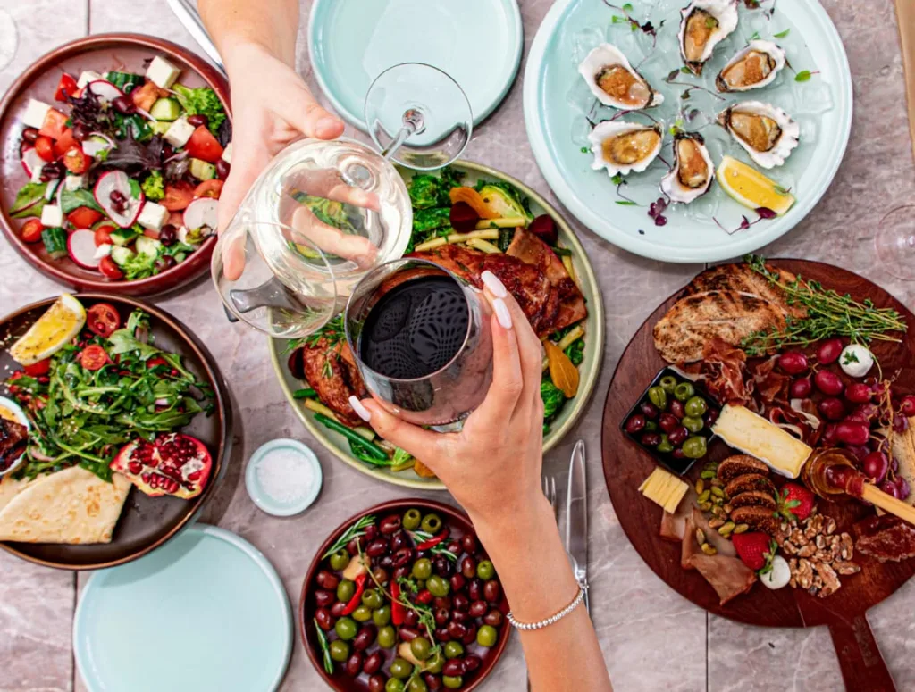 Healthy food served on a table two hands clinking wine cups