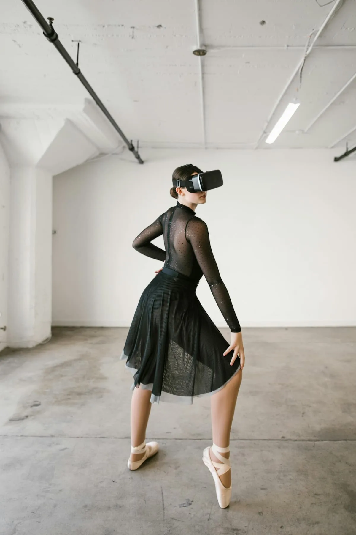 Woman in black transparent dress with VR headset dancing with right Toe forward