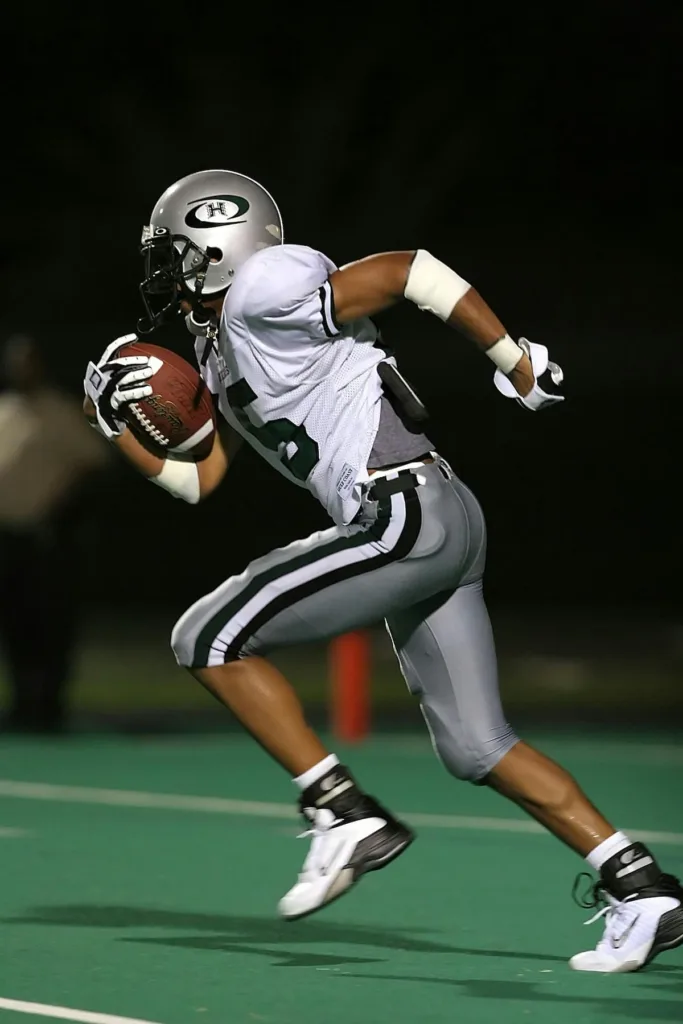 American football player running with the ball in hand inside the field