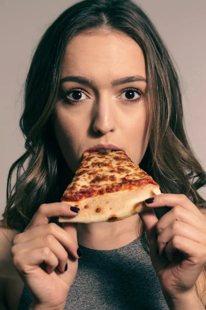 Woman holding and eating pizza slice