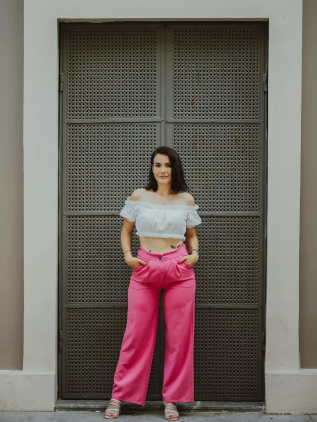 Woman in white off shoulder top and pink bottoms with hands in pockets