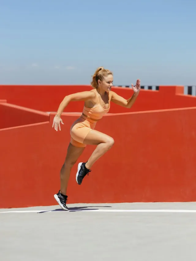 woman in orange sports bra and shorts practicing running