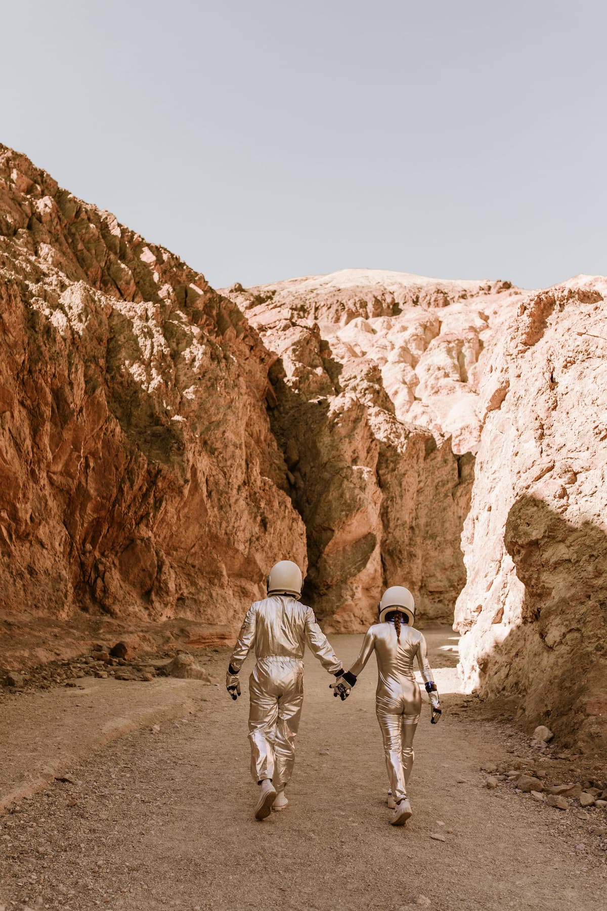 One couple walking with hands held in a out of the world like place with astronaut like suit Future of Space Tourism
