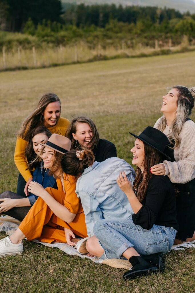 7 young girls in a open field sitting and chatting and giggling