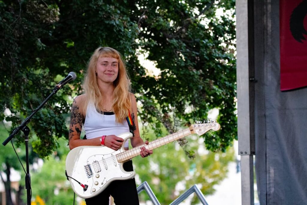 a woman artist with white guitar in front of mike